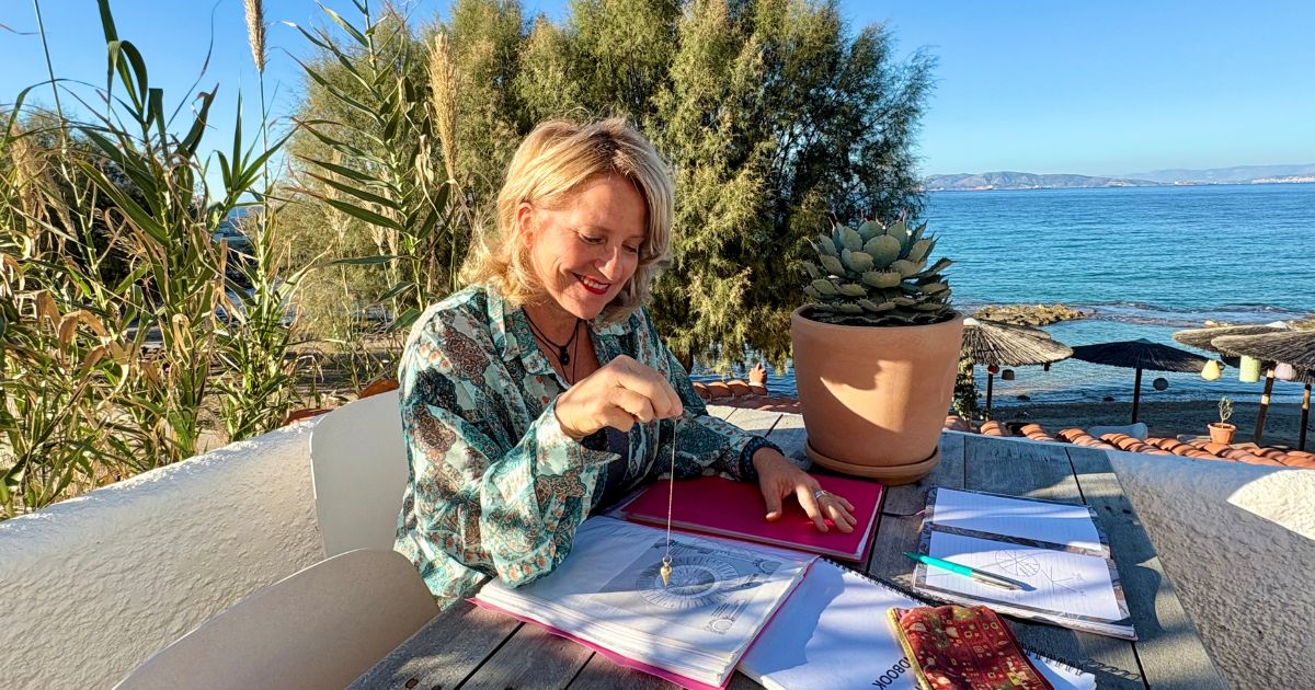 Lizzy using a pendulum at The Beachhouse on Aegina Island, focusing on clarity and aligned decision-making by the sea.